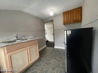 kitchen with sink, stainless steel fridge, and vaulted ceiling