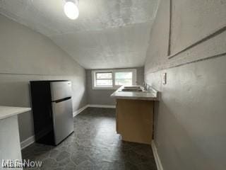 kitchen with lofted ceiling, sink, and stainless steel fridge