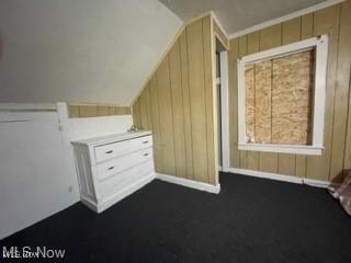 additional living space featuring vaulted ceiling and wood walls