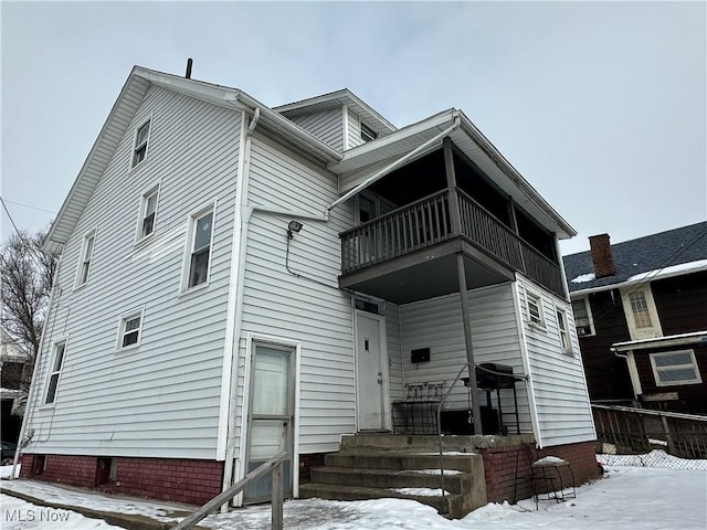 snow covered rear of property with a balcony