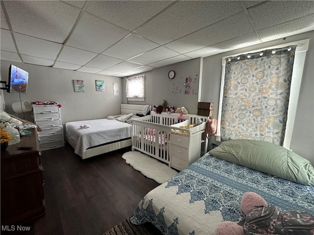 bedroom with a paneled ceiling and dark hardwood / wood-style flooring