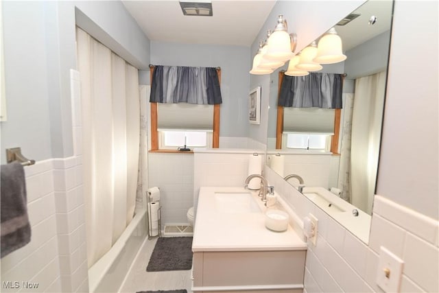 full bathroom with vanity, tile walls, shower / bath combination with curtain, and toilet