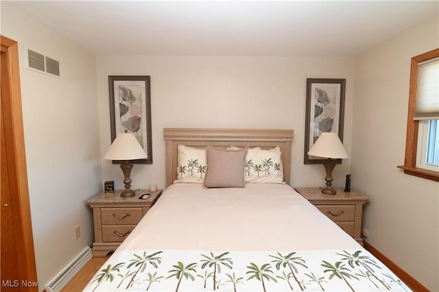 bedroom featuring baseboard heating and wood-type flooring