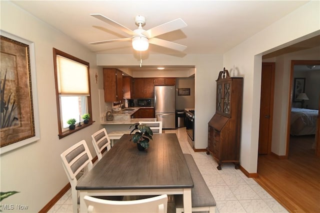 dining area featuring sink, light tile patterned floors, and ceiling fan