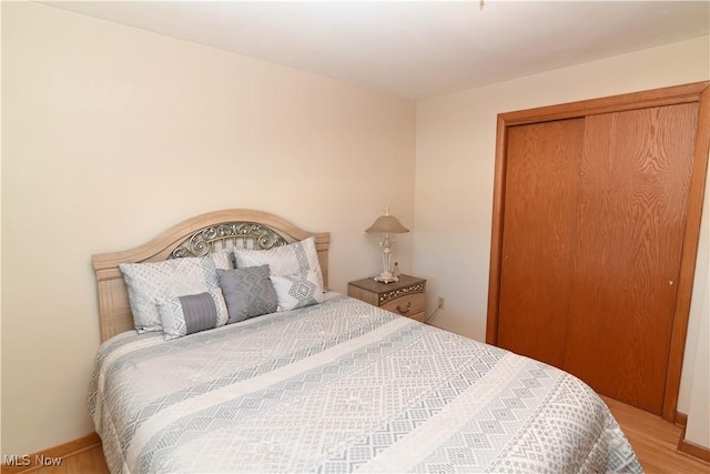 bedroom with light hardwood / wood-style floors and a closet