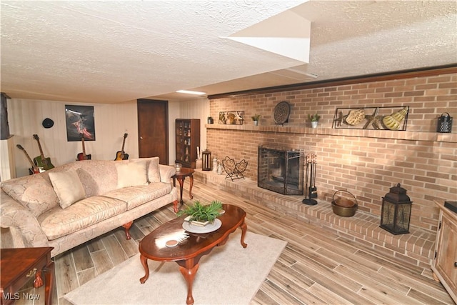 living room with a fireplace, a textured ceiling, and light hardwood / wood-style flooring