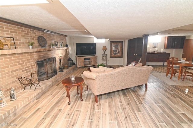 living room with hardwood / wood-style flooring, a brick fireplace, and a textured ceiling