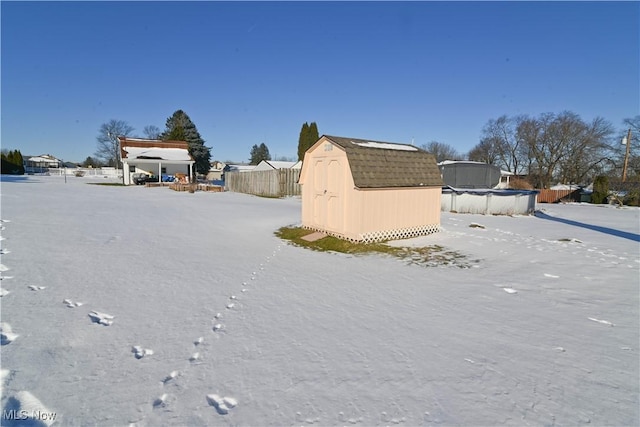 yard covered in snow featuring a covered pool and a shed