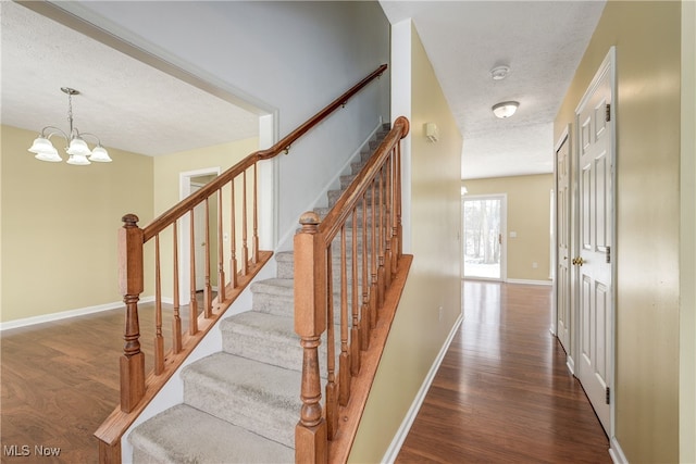 stairway with hardwood / wood-style flooring and a chandelier