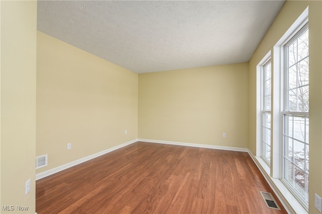 unfurnished room featuring hardwood / wood-style floors and a textured ceiling