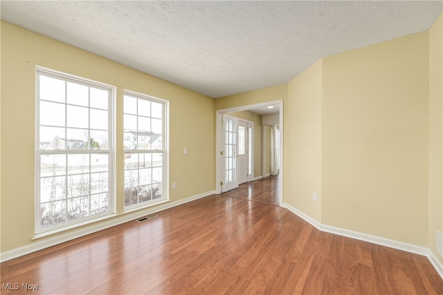 unfurnished room featuring wood-type flooring, a textured ceiling, and plenty of natural light