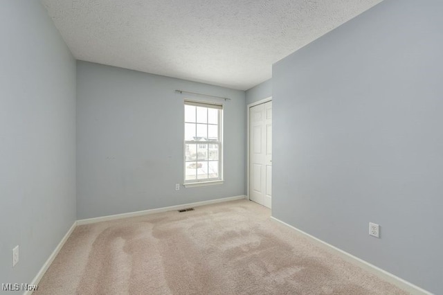 carpeted empty room featuring a textured ceiling