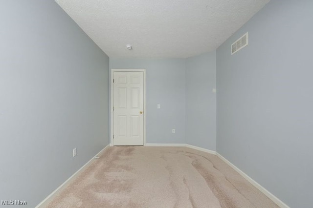 carpeted empty room with a textured ceiling