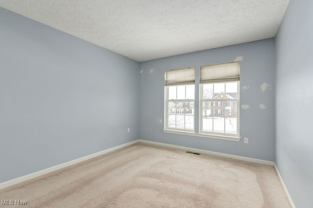 carpeted empty room with a textured ceiling