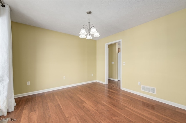 unfurnished room featuring wood-type flooring, a chandelier, and a textured ceiling