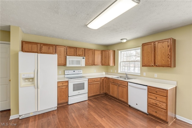 kitchen with dark hardwood / wood-style floors, sink, a textured ceiling, and white appliances