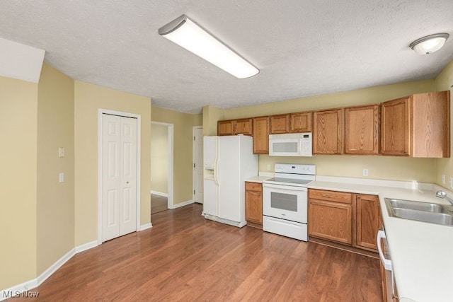 kitchen featuring sink, white appliances, dark wood-type flooring, and a textured ceiling