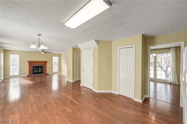 unfurnished living room featuring a healthy amount of sunlight, dark wood-type flooring, and a notable chandelier