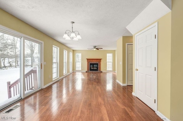 unfurnished living room featuring plenty of natural light, a brick fireplace, and a textured ceiling