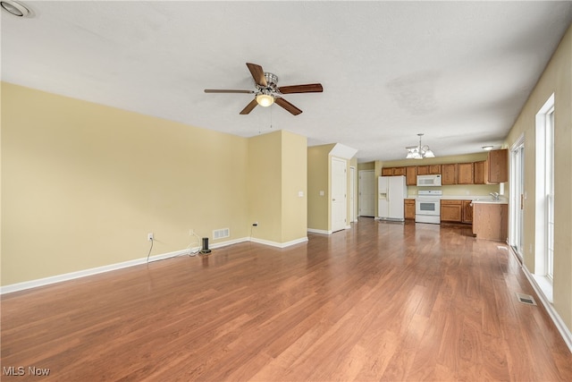 unfurnished living room with wood-type flooring, sink, and ceiling fan with notable chandelier