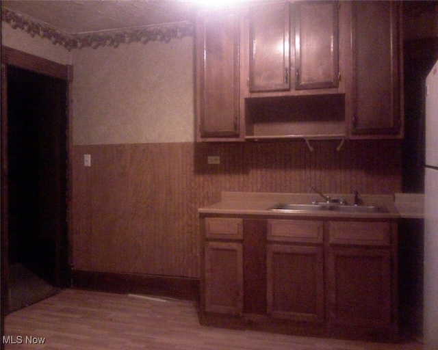 kitchen with sink, wooden walls, and light hardwood / wood-style floors