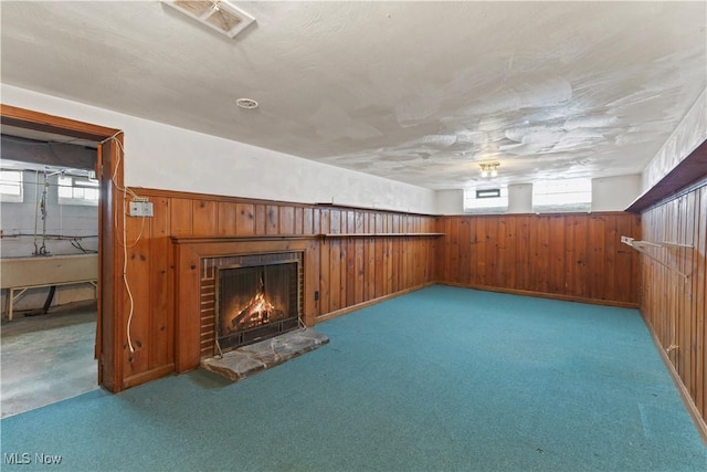 additional living space featuring a brick fireplace, wooden walls, and light colored carpet