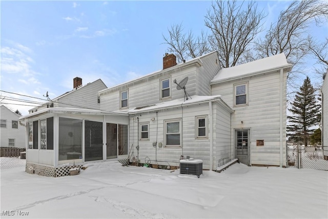 snow covered property with a sunroom and central air condition unit