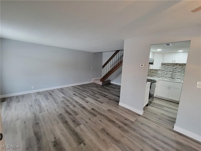 unfurnished living room featuring sink and light hardwood / wood-style floors