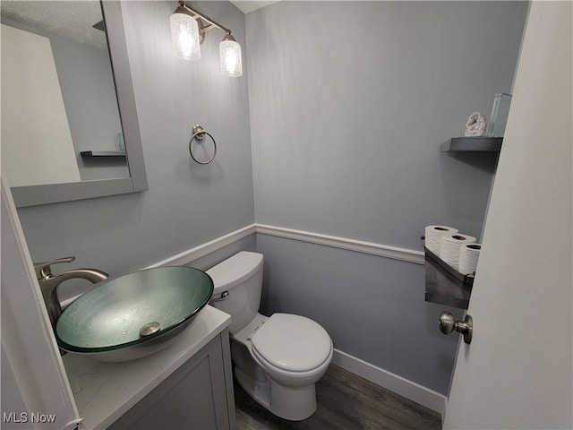 bathroom with vanity, wood-type flooring, a textured ceiling, and toilet