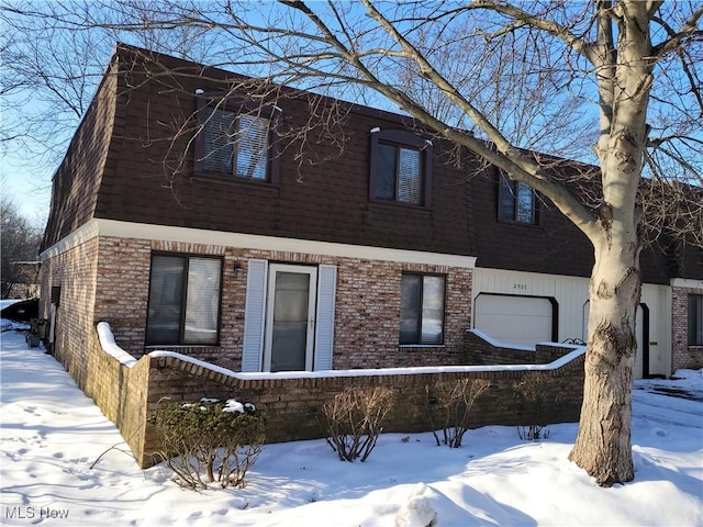 snow covered property with a garage