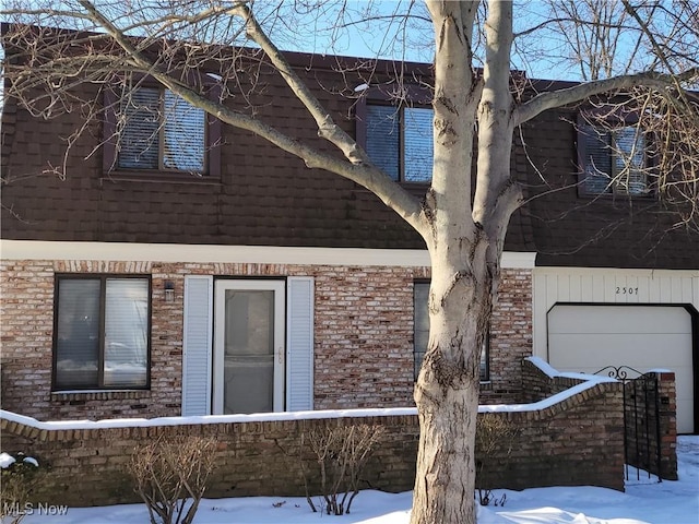 snow covered property with a garage