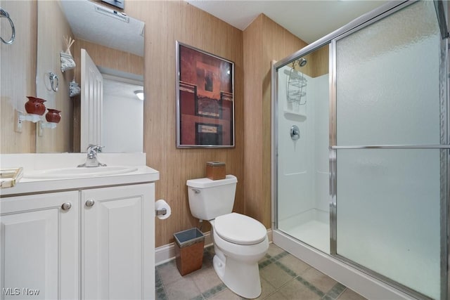 bathroom with vanity, toilet, a shower with shower door, and tile patterned flooring