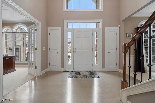 carpeted entrance foyer with a towering ceiling