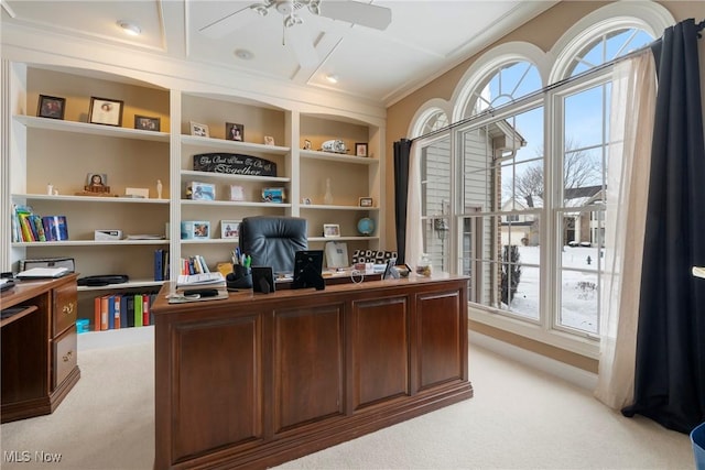 carpeted office with built in shelves and ceiling fan