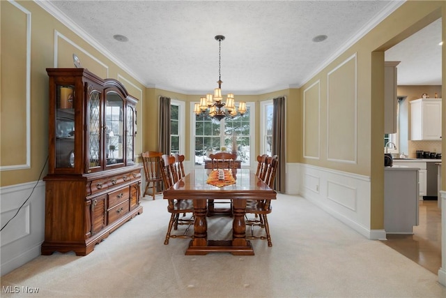 carpeted dining room with crown molding, sink, a textured ceiling, and a chandelier