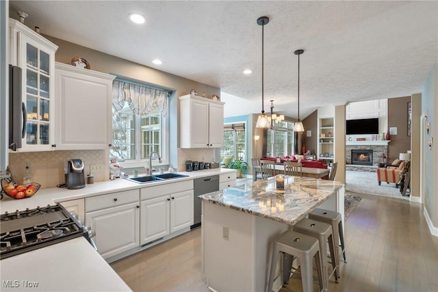 kitchen with pendant lighting, appliances with stainless steel finishes, sink, and white cabinets