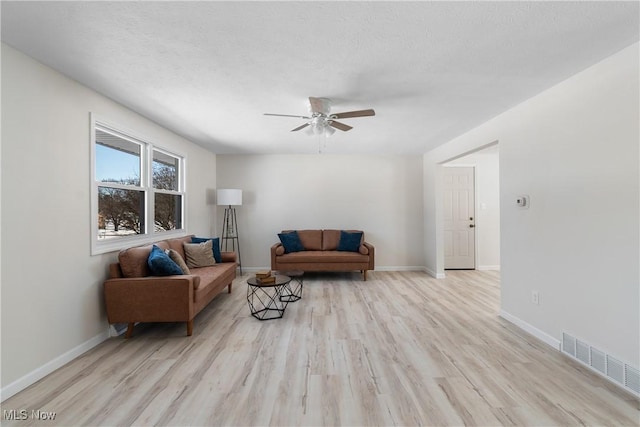 living room featuring ceiling fan, a textured ceiling, and light hardwood / wood-style floors