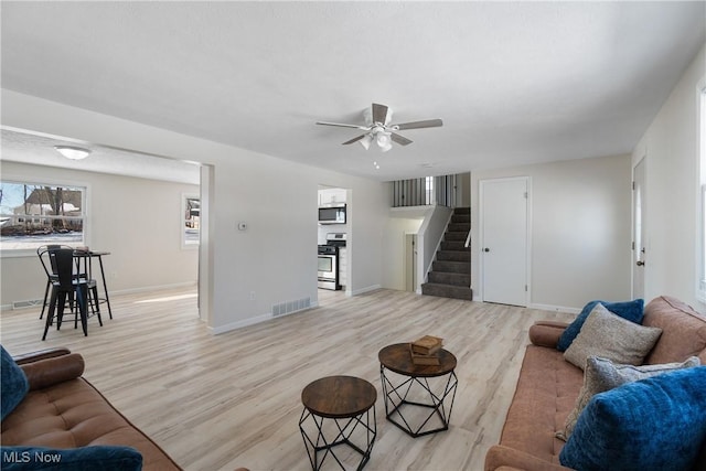 living room with light hardwood / wood-style flooring and ceiling fan