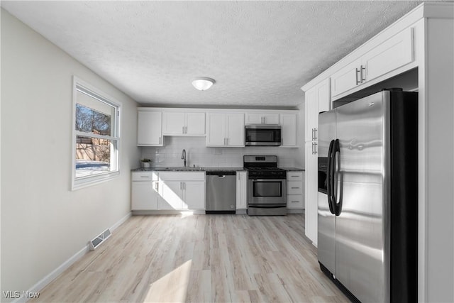 kitchen featuring stainless steel appliances, tasteful backsplash, sink, and white cabinets