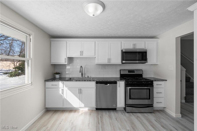 kitchen with appliances with stainless steel finishes, sink, and white cabinets