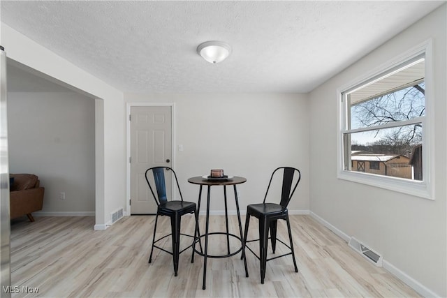 dining space with light hardwood / wood-style flooring and a textured ceiling