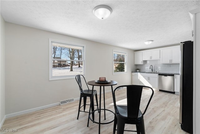 dining room with sink, a textured ceiling, and light wood-type flooring