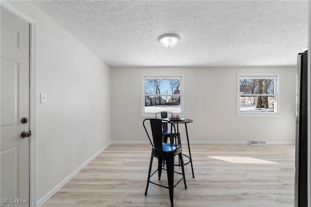 dining room featuring plenty of natural light, light hardwood / wood-style flooring, and a textured ceiling