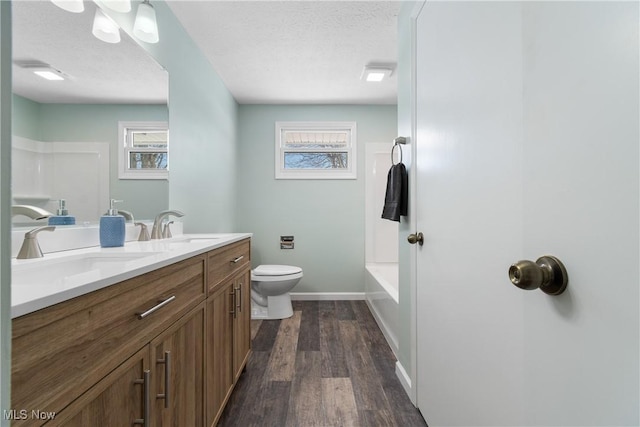 full bathroom with vanity, hardwood / wood-style flooring, plenty of natural light, and a textured ceiling