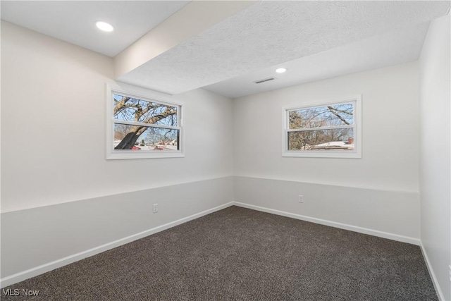 unfurnished room featuring a textured ceiling and dark colored carpet