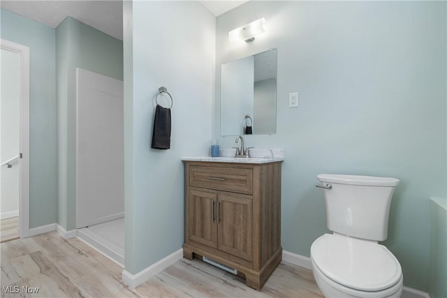 bathroom with a shower, wood-type flooring, vanity, and toilet