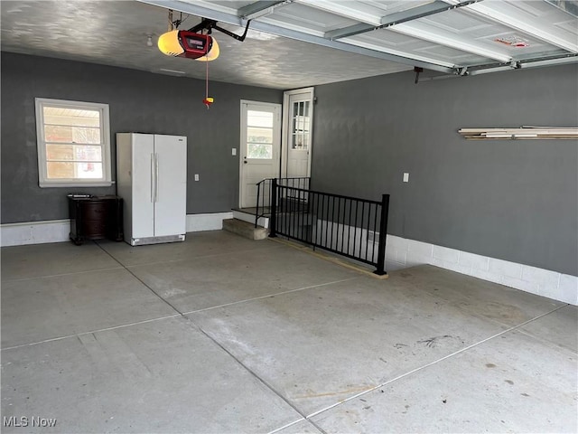 garage with a garage door opener and white fridge