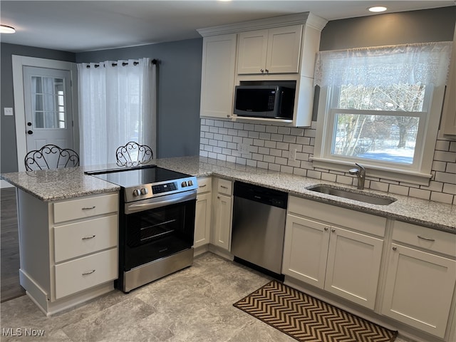 kitchen featuring sink, backsplash, kitchen peninsula, stainless steel appliances, and light stone countertops