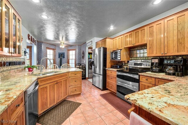 kitchen featuring stainless steel appliances, sink, a textured ceiling, and light tile patterned floors