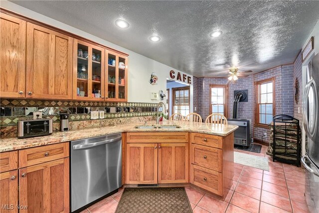 kitchen featuring sink, a wood stove, light tile patterned floors, kitchen peninsula, and stainless steel appliances